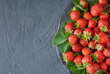 Plate with fresh red srtrawberry on dark background with copy space. Organic food
