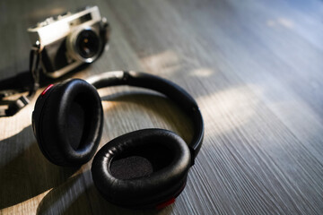 Headphones, and film camera placed on the wood at bedroom in sunset light background. Copy space...