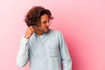 Young caucasian man isolated on pink bakcground covering ears with hands.