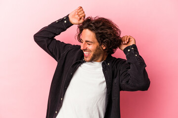 Young caucasian man isolated on pink bakcground celebrating a special day, jumps and raise arms with energy.