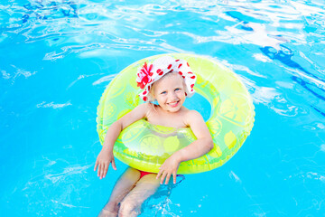 baby girl swims in the pool with an inflatable yellow circle in summer, the concept of travel and recreation and smiles in panama
