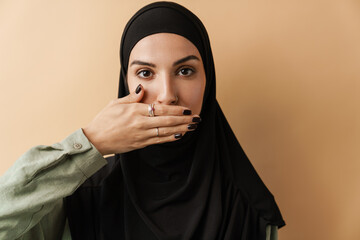 A portrait of the muslim woman covering her mouth with one hand