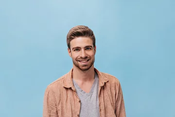 Foto op Plexiglas Fashionable man in good mood with short hairstyle in cool clothes smiling and looking into camera on isolated background.. © Look!