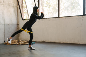 Young muslim sportswoman in hijab doing exercise while working out