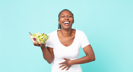 laughing out loud at some hilarious joke and holding a salad