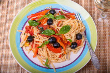 Linguini pasta with pepper, basil and olive sauce - portion in a plate, close-up