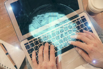 Double exposure of man's hands typing over computer keyboard and brain hologram drawing. Top view. Ai and data technology concept.