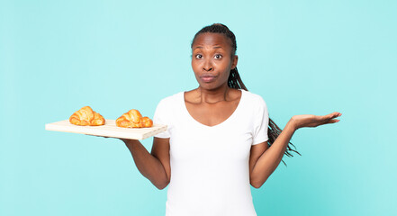 feeling puzzled and confused and doubting and holding a croissant tray