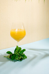 vibrant yellow cold drink in a glass.summer aesthetic.tropic idea.blue and beige background with shadows