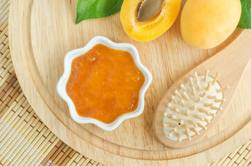 Homemade apricot face or hair mask in a small white bowl and wooden hairbrush. Natural beauty treatment and spa recipe. Top view, copy space.