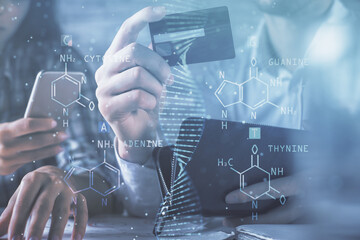 Double exposure of man and woman on-line shopping holding a credit card and DNA hologram drawing....