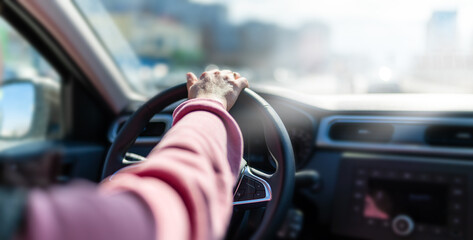 The hand of a man holding a steering wheel in the car.