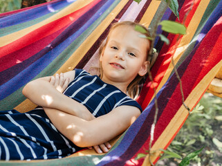 Fototapeta na wymiar Cute girl in the colorful hammock summer background, summer holiday outdor activities