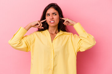 Young caucasian woman isolated on pink background covering ears with fingers, stressed and desperate by a loudly ambient.