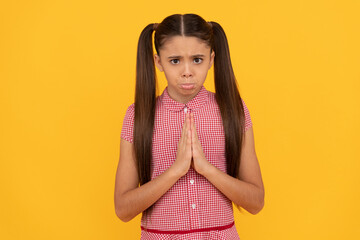 Unhappy girl prayer plead holding palms together in prayer gesture yellow background, pleading