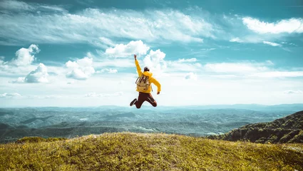 Foto op Plexiglas Hiker with backpack raising hands jumping on the top of a mountain - Successful man with arms up enjoying victory - Sport and success concept   © Davide Angelini