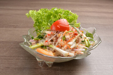 cold thai style spicy chilli sauce papaya and mango vegetable salad and shrimp in bowl on wood table asian Thai appetiser halal menu