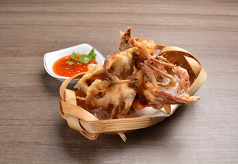 deep fried soft shell crab in bamboo basket with spicy peanut chilli sauce on wood table asian Thai appetiser halal menu