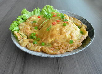 golden stir fried egg omelette with seafood and meat on wood table asian Thai appetiser halal menu