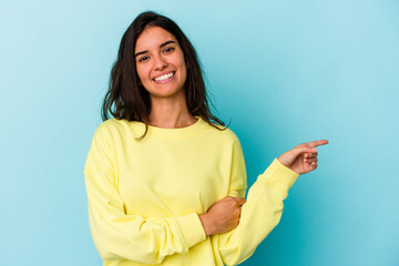 Young caucasian woman isolated on blue background smiling cheerfully pointing with forefinger away.
