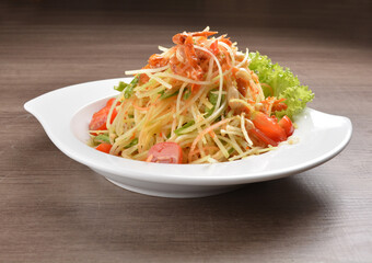 cold thai style spicy chilli sauce papaya and mango vegetable salad and shrimp in bowl on wood table asian Thai appetiser halal menu