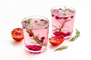 Glasses of cranberry lemonade and red oranges with rosemary