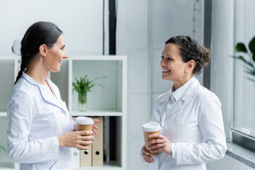 Doctor with paper cup talking to african american colleague