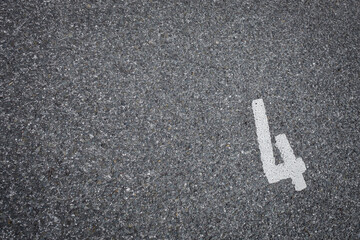 sign on asphalt, number four painted on grey road like a parking place, no person,  