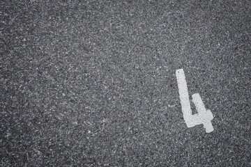 sign on asphalt, number four painted on grey road like a parking place, no person,