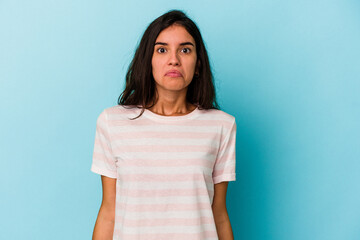 Young caucasian woman isolated on blue background shrugs shoulders and open eyes confused.