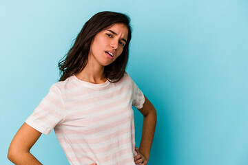 Young caucasian woman isolated on blue background frowning face in displeasure, keeps arms folded.