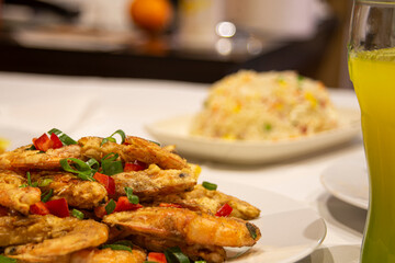 Plate of fried shrimp in tempura with chopped vegetables on table in Chinese restaurant.