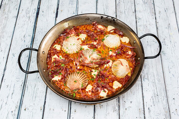 Paella served in paella with scallops and serrano ham ready to sit down to eat