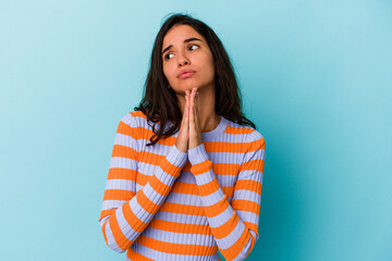 Young caucasian woman isolated on blue background praying, showing devotion, religious person...