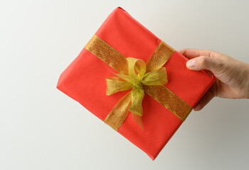 female hand are holding a red gift box on a gray background, happy birthday concept