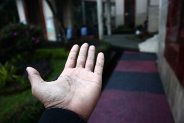 the hand of someone who is calling in a mosque courtyard