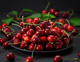 Fototapeta na wymiar ripe red cherries in a ceramic plate on a black wooden table