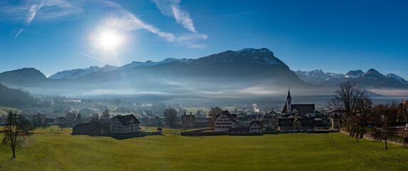 Die Sonne scheint in eine nebelverhangenes Tal in den Schweizer Bergen
