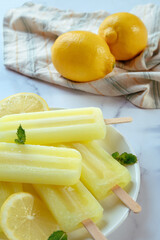 lemon popsicles on a flat linen ice with fresh lemons in the background