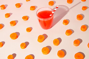 Creative layout made of carrot juice surrounded by carrot slices. Colorful background summer fresh idea.