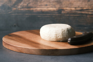 round shape fresh cheese on a chopping board on table 