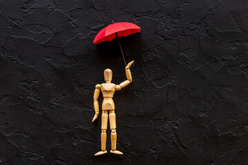 Social protection and insurance concept. Umbrella cover wooden mannequin figure