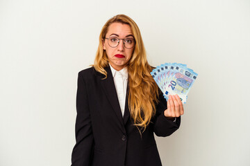 Caucasian business woman holding bills isolated on white background shrugs shoulders and open eyes confused.