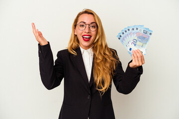 Obraz premium Caucasian business woman holding bills isolated on white background receiving a pleasant surprise, excited and raising hands.