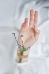 Female hand with forget me not or scorpion grass flowers applied with patch on white background, top view with copy space. Wellness or cosmetics concept, spring floral aesthetics. High quality photo