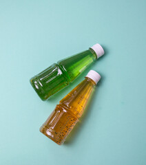 Kiwi juice and mango juice in transparent plastic bottles with white lids