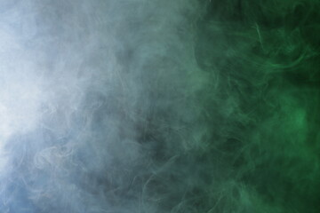 Artificial smoke in grey-green light on black background