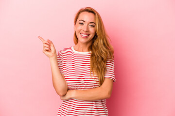 Caucasian blonde woman isolated on pink background smiling cheerfully pointing with forefinger away.