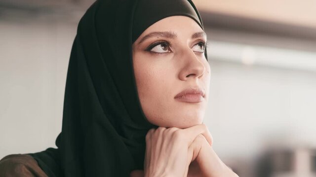 A close-up view of an Arabian woman is thinking about something sitting inside
