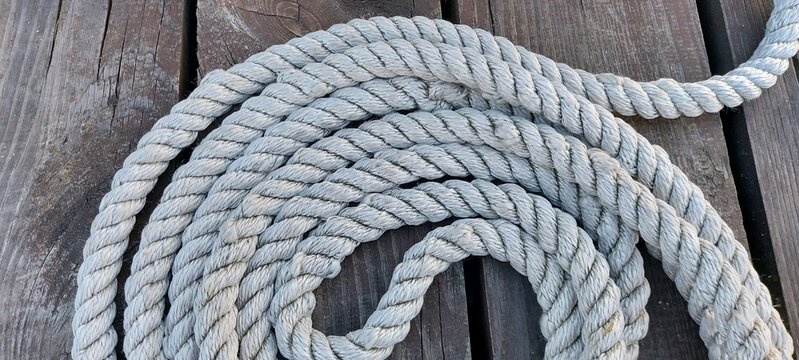 White mooring rope in several skeins close-up on a wooden pier.